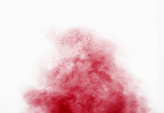 A imagem mostra um líquido vermelho caindo de um recipiente em um fundo branco. O líquido parece ser uma mistura de vermelho e branco, com algumas bolhas visíveis no líquido.
