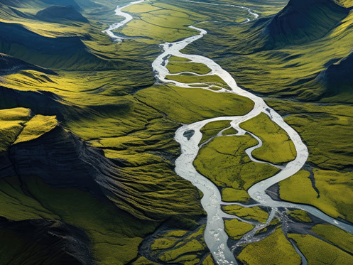 A imagem mostra um rio atravessando um vale verde cercado por montanhas. O rio serpenteia pelo vale, criando um cenário sereno e pacífico.