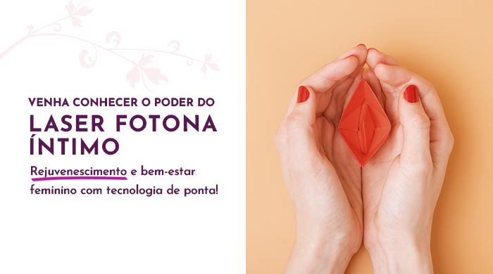 Mãos femininas com unhas pintadas de vermelho seguram uma representação estilizada de uma vulva vermelha em fundo laranja claro.